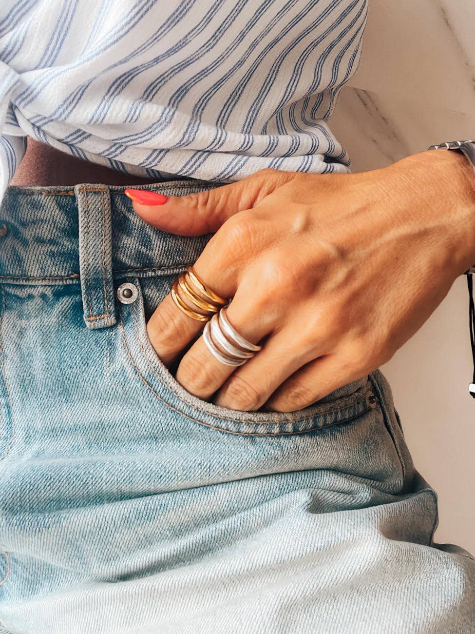 Person wearing a striped shirt and denim jeans with visible jewelry.