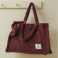 Maroon plush bag with a visible brand label on a beige background