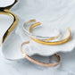 Gold and silver bangles on a white shell with a marble background