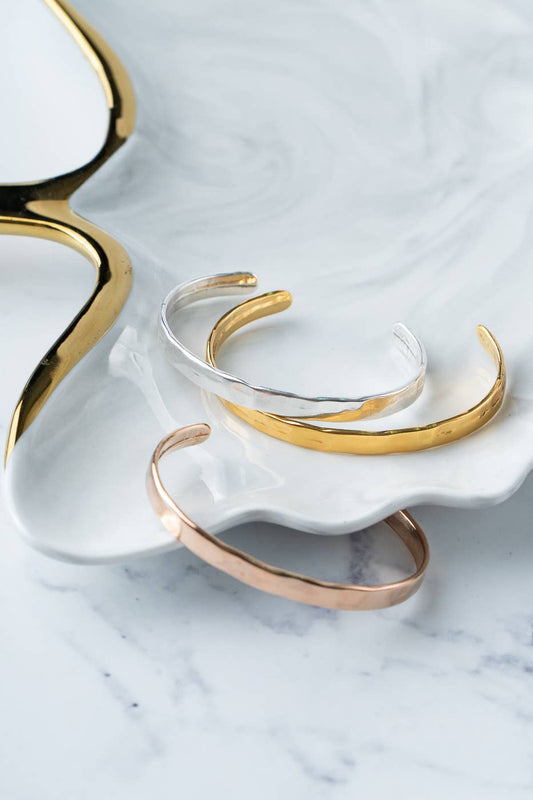 Gold and silver bangles on a white shell with a marble background