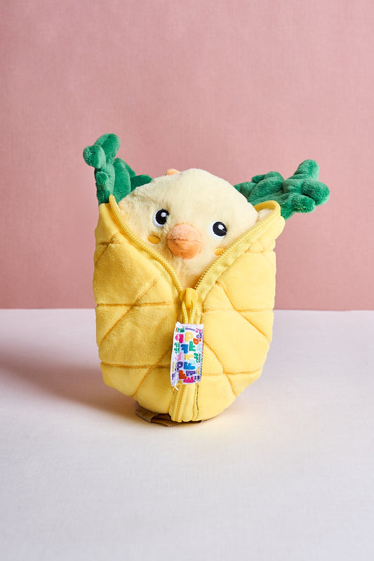 Plush toy resembling a bird wrapped in yellow fabric with green leaves on a pink background